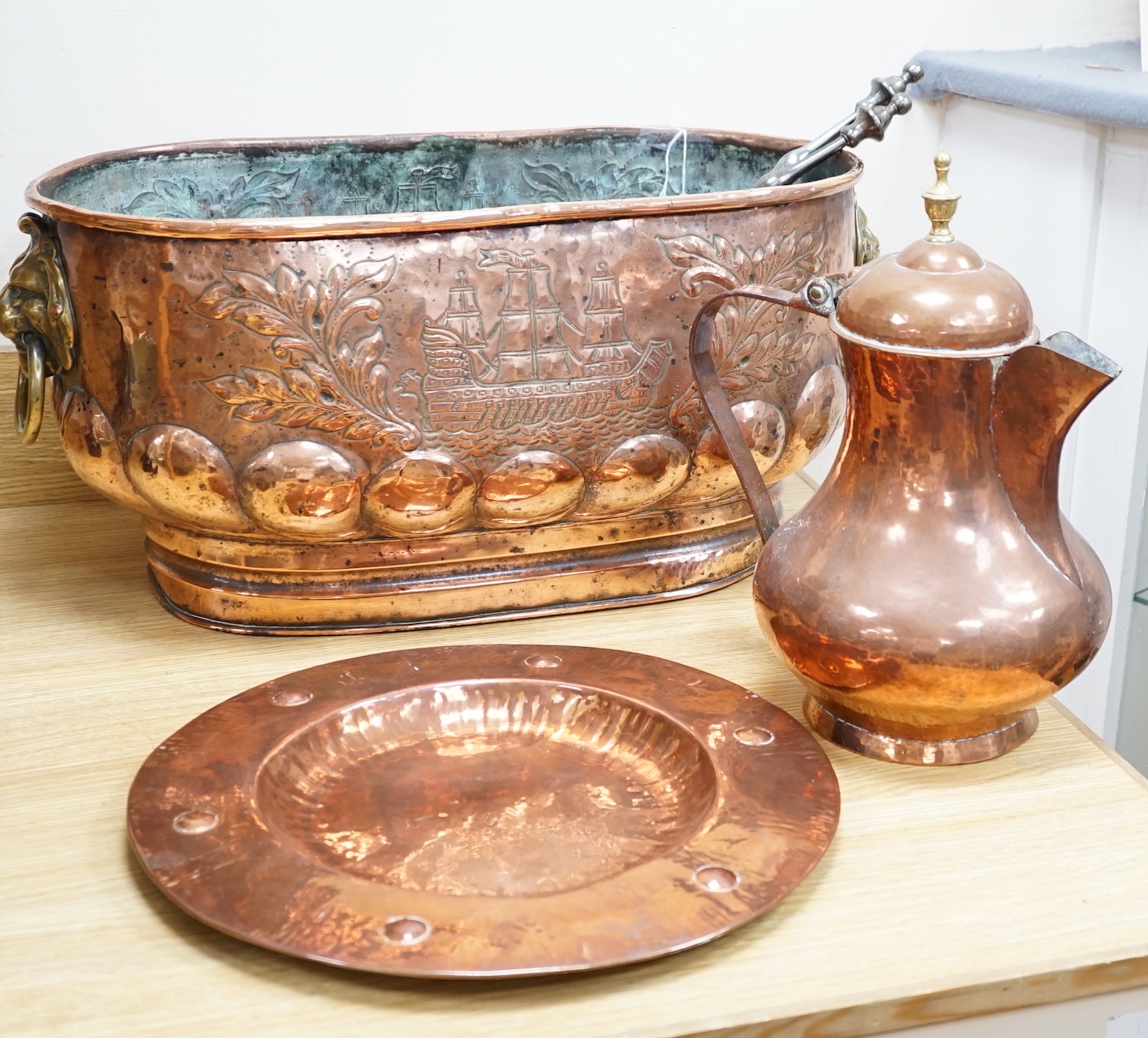 An 18th century Dutch beaten copper planter of elongated form with lion mask handles, beaten ship decoration and heavy gadrooning, 62cm long (Provenance Bonhams Chester 31/10/03). A large 19th century copper jug, baluste